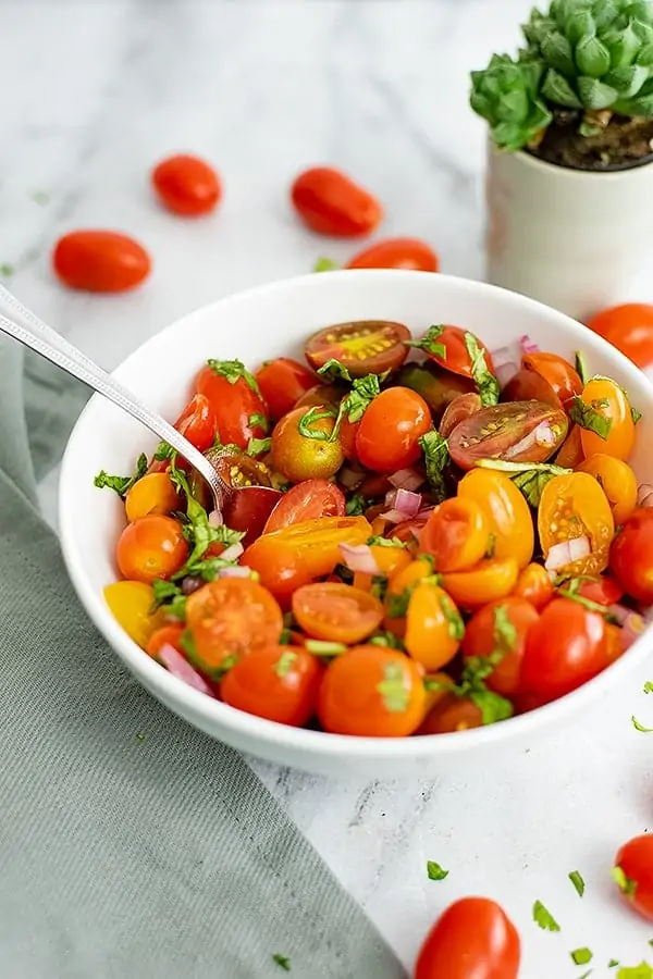 Bowl of tomato basil salad over a grey napkin
