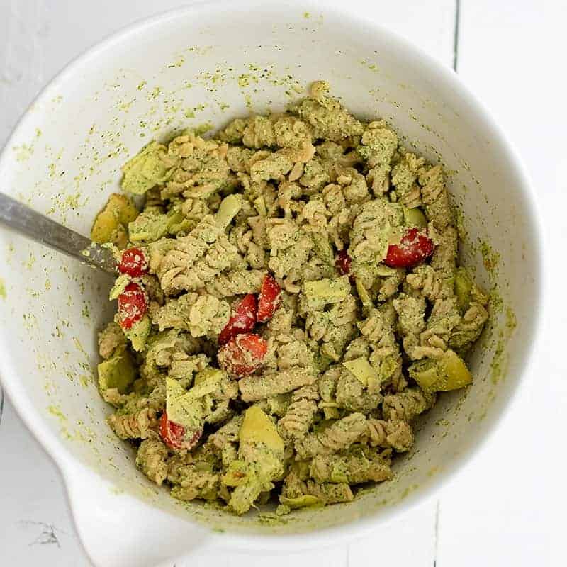 Large white bowl filled with artichoke pesto pasta after mixing