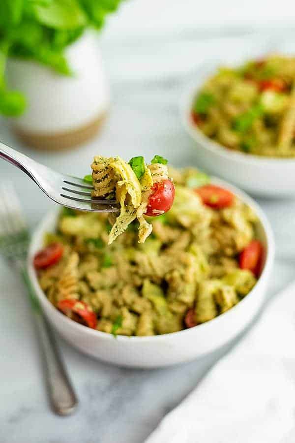 Fork holding a bite of artichoke pesto pasta