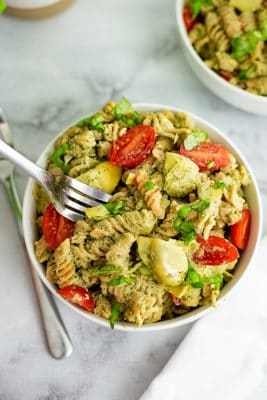 Silver fork in a bowl of artichoke pesto pasta.