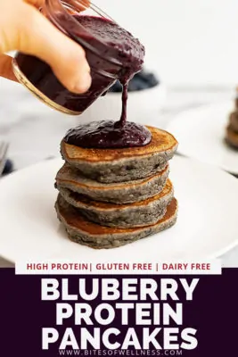 stack of 4 pancakes being with blueberry syrup poured over top