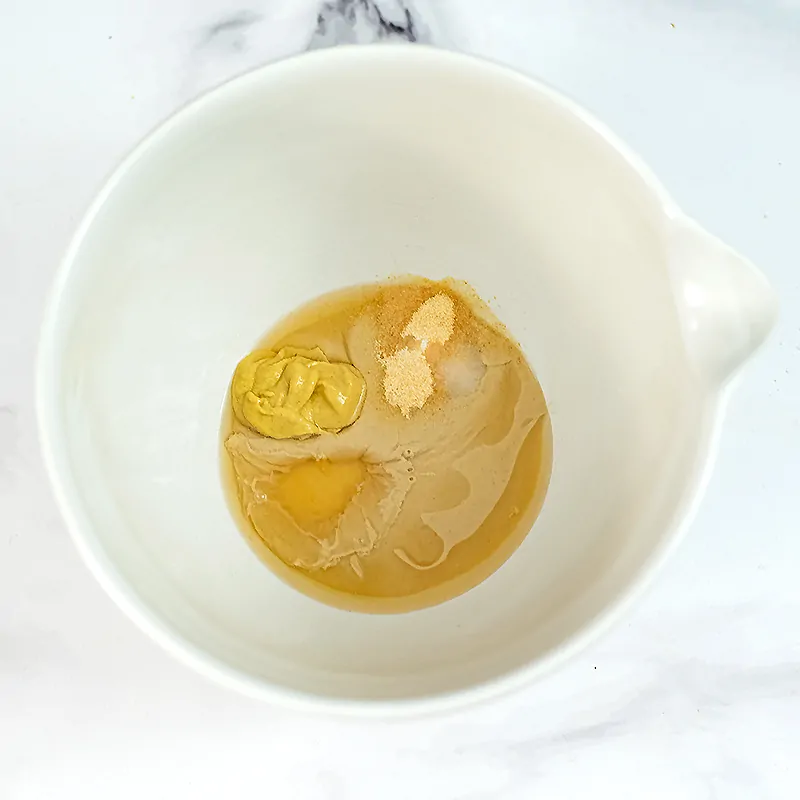 Large white bowl filled with lemon tahini dressing ingredients