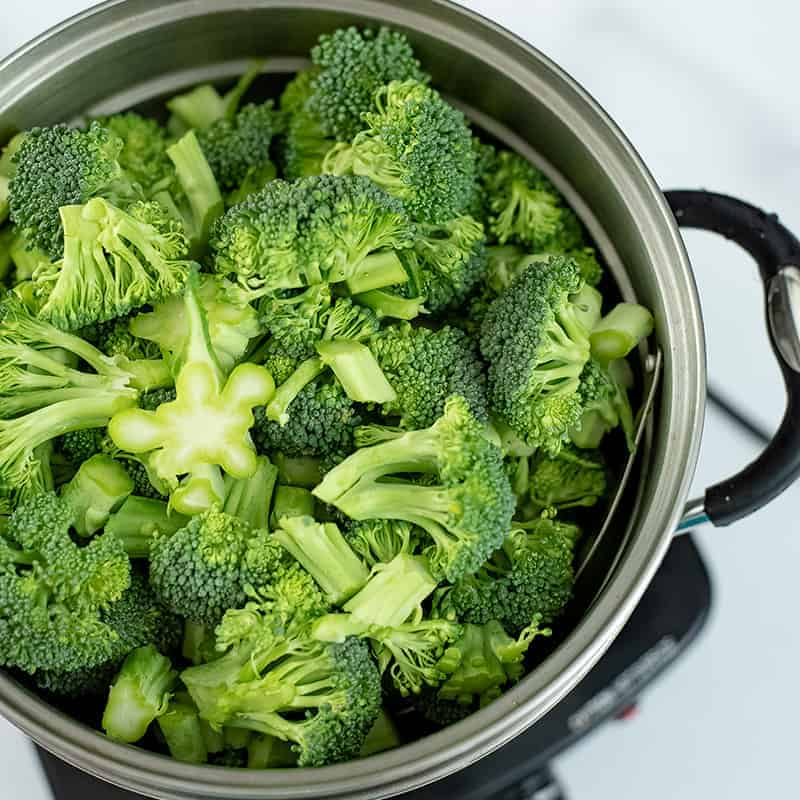 Broccoli florets in a steamer basket.