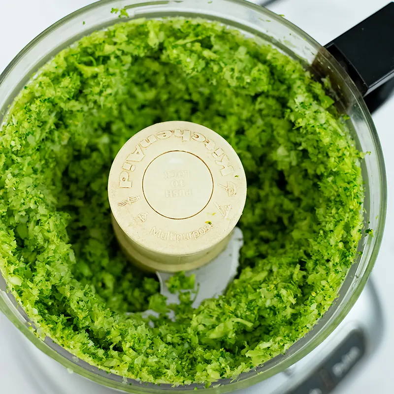 Food processor filled with riced broccoli.