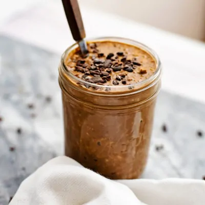 Mason jar filled with mocha overnight oats and wooden spoon