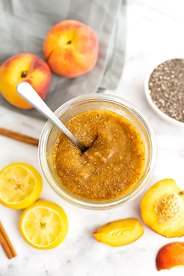 Jar of peach chia jam with a spoon in the jar
