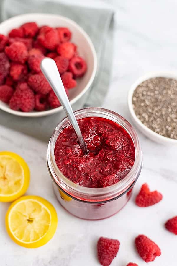 Jar of raspberry chia jam with a spoon in the jar