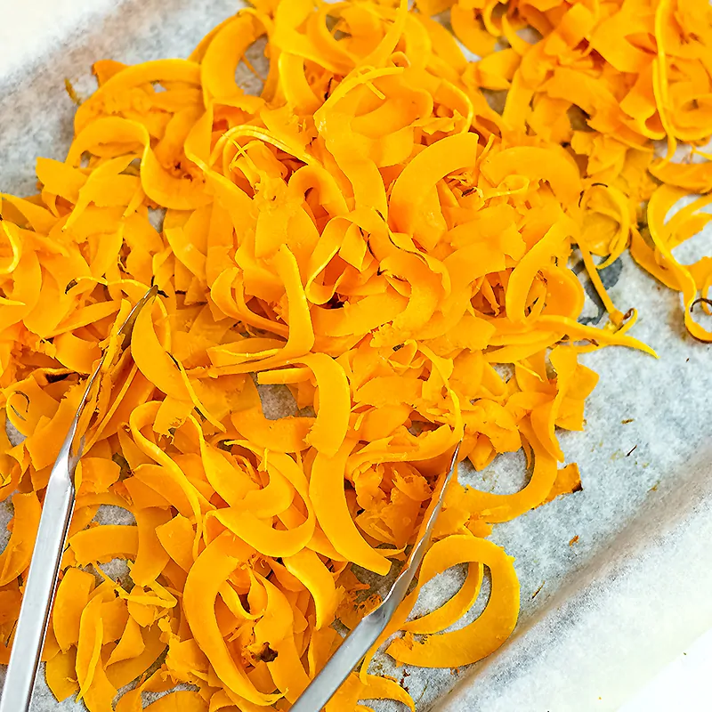 Cooked butternut squash noodles on a baking sheet with tongs
