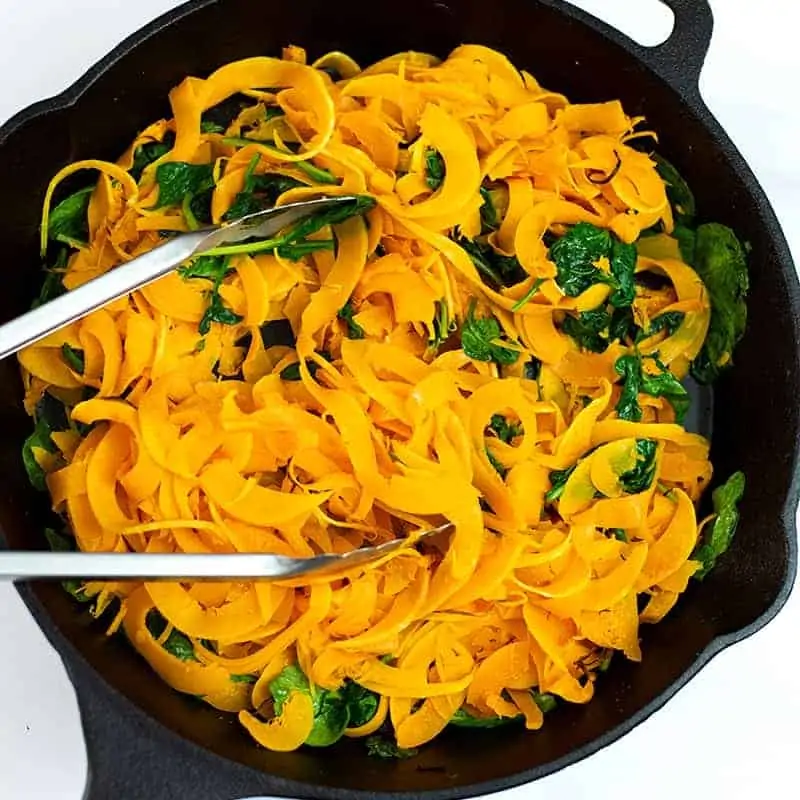 Spiralized butternuts squash and arugula in cast iron skillet.