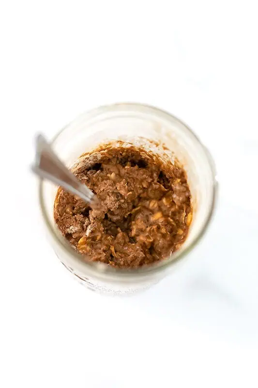 Spoon resting in a jar filled with mocha overnight oats.