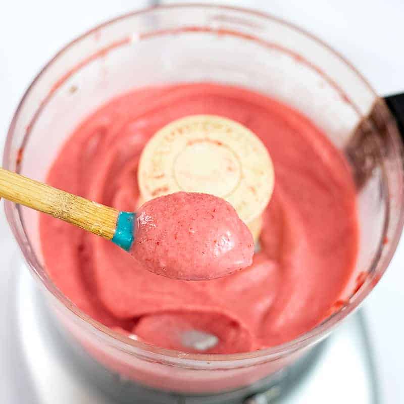Spoon holding up the strawberry frozen yogurt mixture