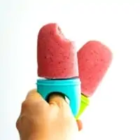 Hand holding 2 strawberry popsicles, one has bite taken