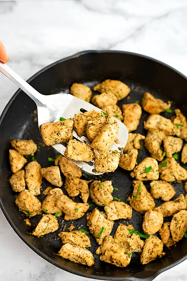 Silver spatula picking up Italian Chicken from the skillet.