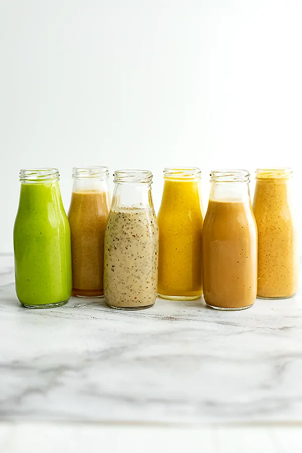 Glass bottles lined up with 6 Healthy Salad Dressing Recipes