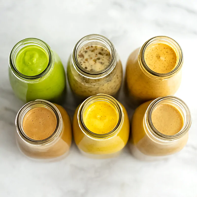 Overhead of 6 healthy salad dressing recipes in bottles