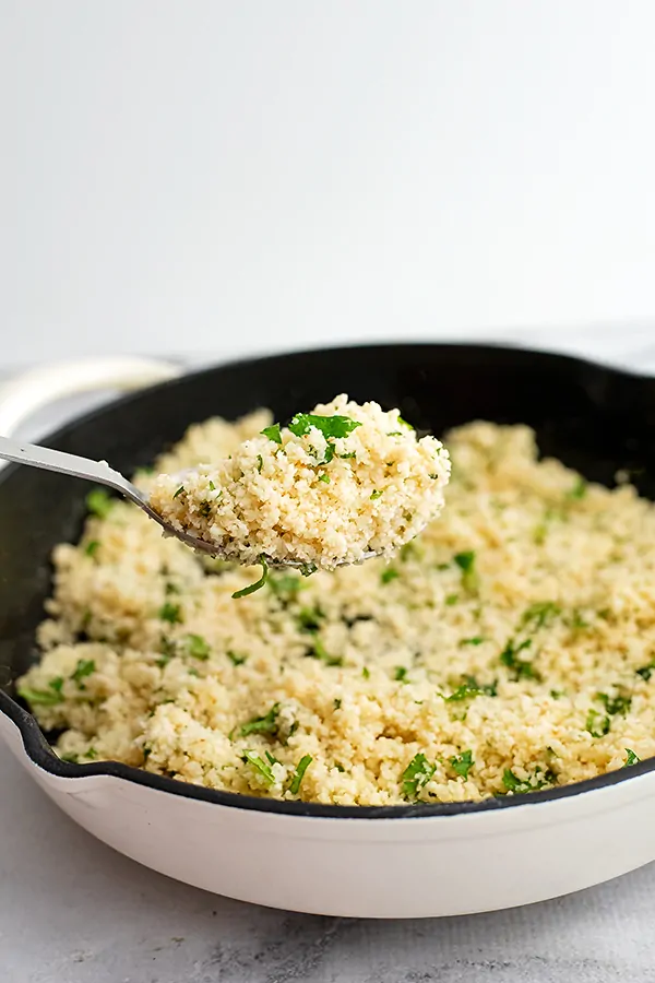 Large silver spoon scooping out a serving of cilantro lime cauliflower rice.