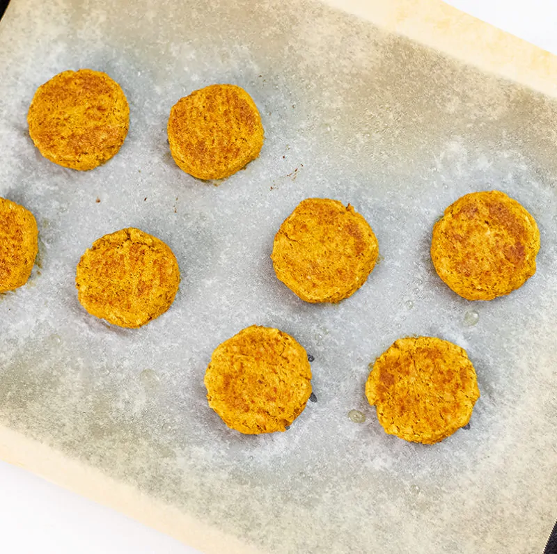 Cooked curry salmon cakes on a parchment paper baking sheet