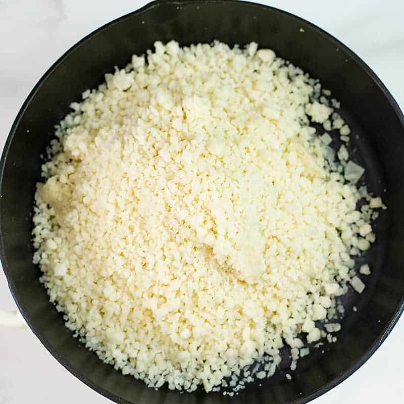 Riced cauliflower in a cast iron skillet.
