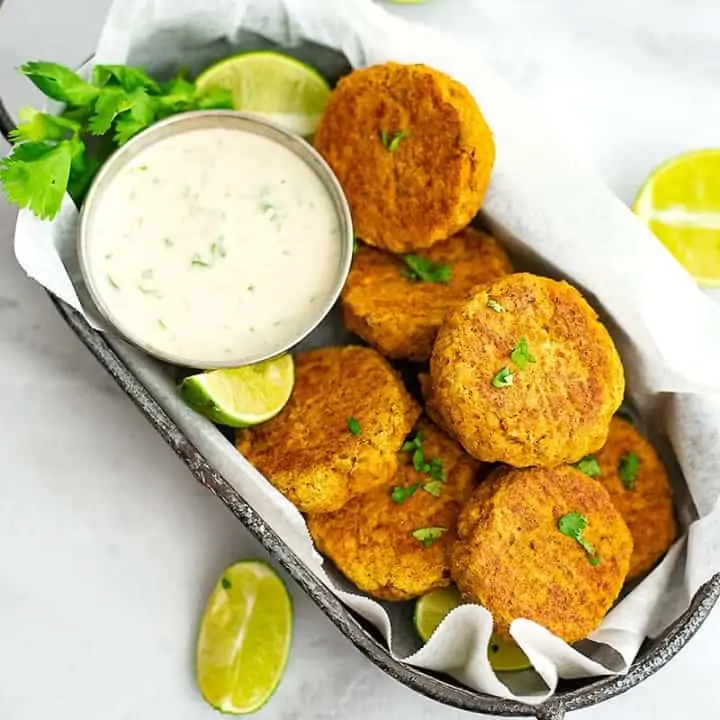 Curry Salmon Cakes in grey basket with cilantro lime yogurt sauce