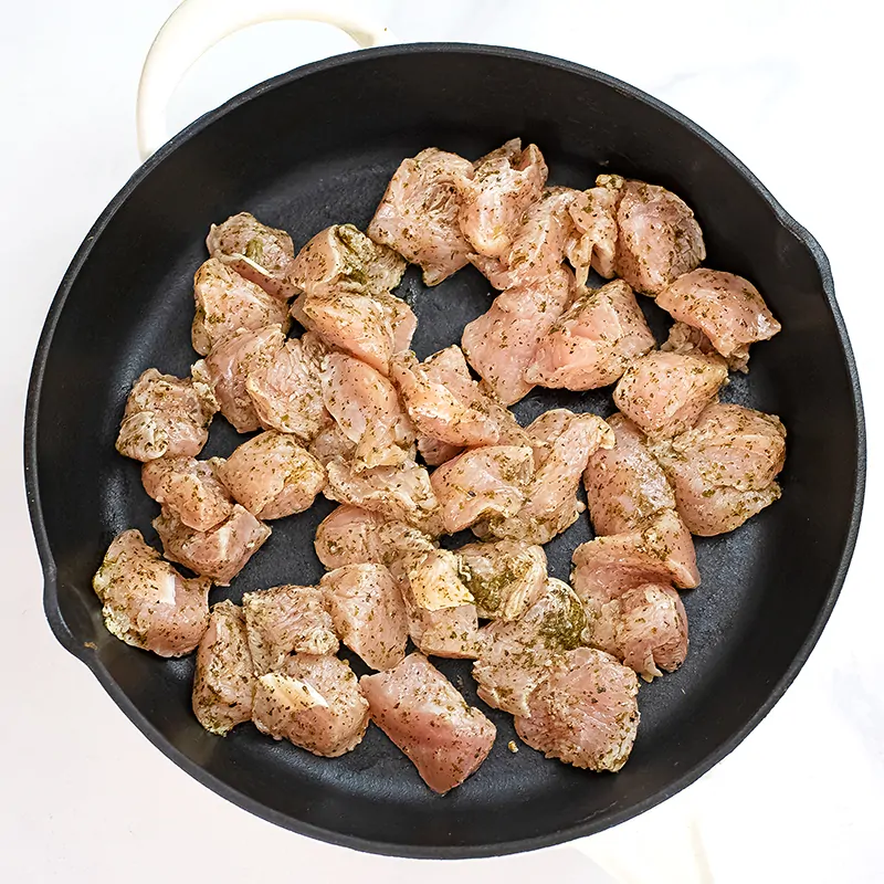 Cast Iron skillet filled with raw Italian Chicken before cooking.