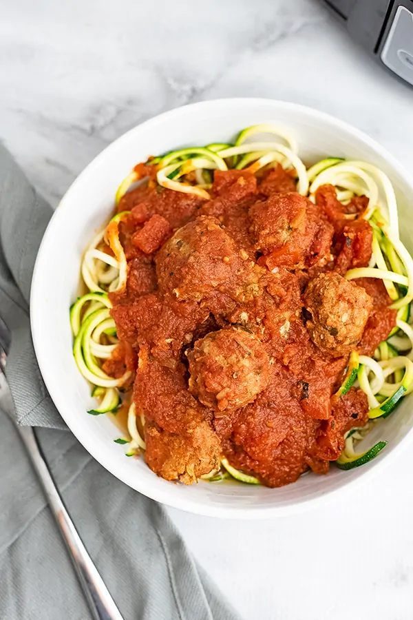Large bowl filled with zucchini noodles topped with Whole30 turkey meatballs.