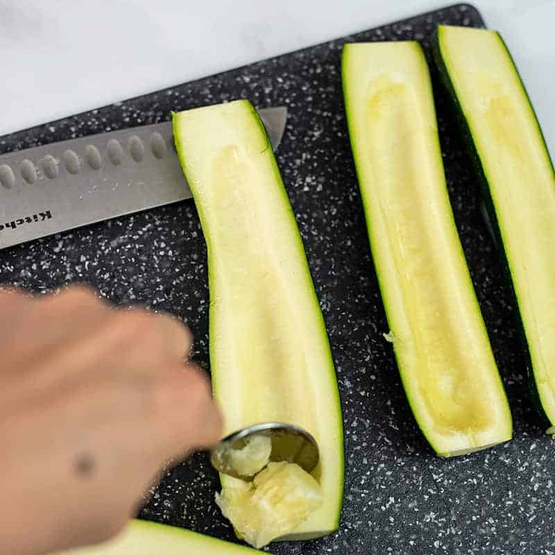 Spoon scooping seeds out of zucchini.