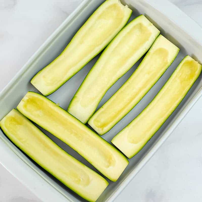Zucchini boats in a casserole dish before cooking.