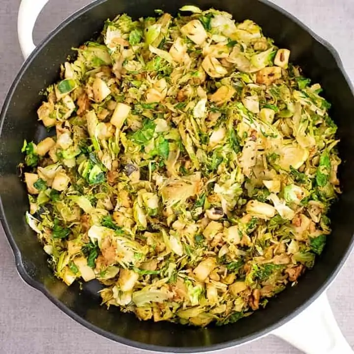 Cast iron skillet filled with apple brussel sprouts hash.