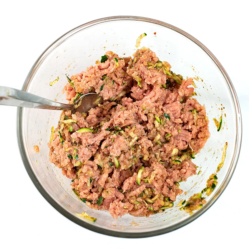 Glass bowl filled with ground turkey mixed with spices.