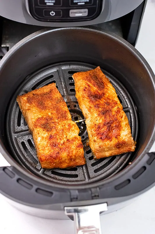Two pieces of salmon in an air fryer basket