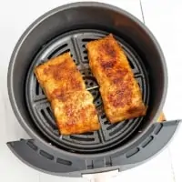 Two pieces of salmon in an air fryer basket
