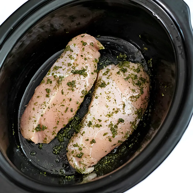 Raw chicken with ranch seasoning in crockpot.