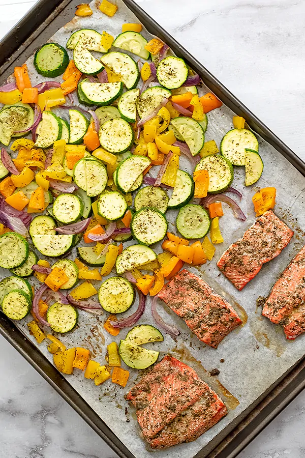 Large sheet pan filled with cooked Greek salmon and vegetables. 
