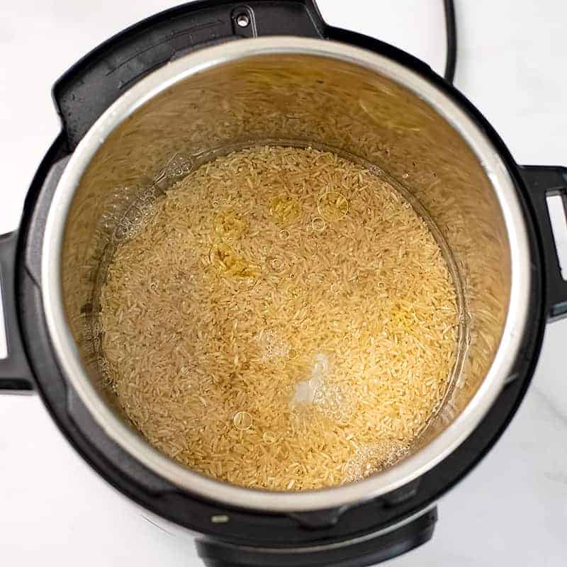 Jasmine rice, water and oil in the instant pot before cooking.
