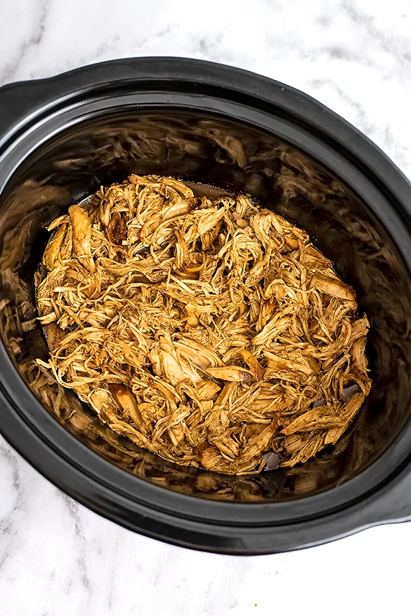 Crock pot filled with shredded balsamic chicken.