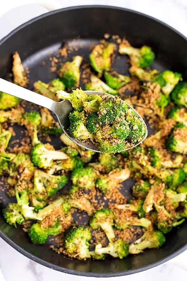 Cast iron skillet filled with broccoli topped with breadcrumbs.