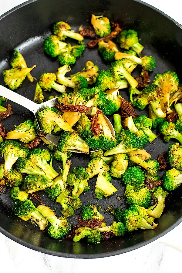 Cast iron skillet filled with sun dried tomato broccoli.