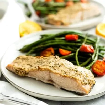 Plate filled with tahini herb crusted salmon, green beans and tomatoes.