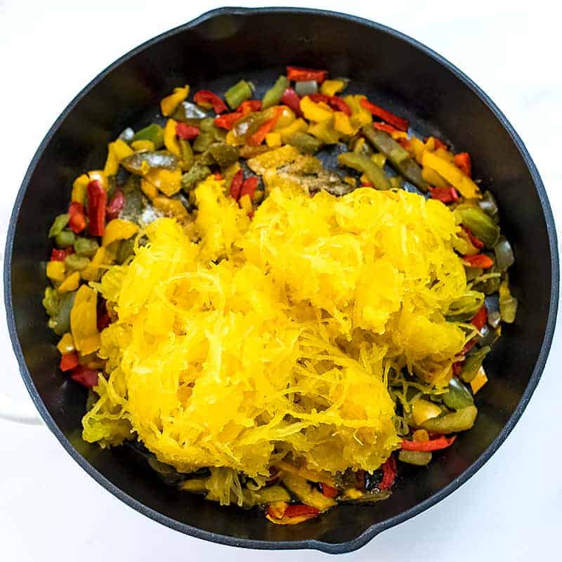 Cast iron skillet with cooked peppers and spaghetti squash.