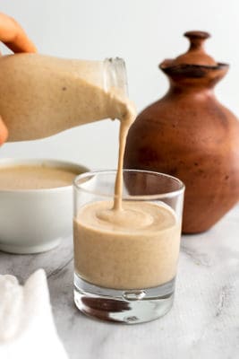 Peanut butter smoothie being poured into a glass.