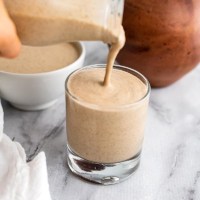 Peanut butter smoothie being poured into a glass.