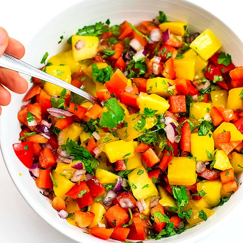 Large bowl of mango salsa with spoon in the bowl.