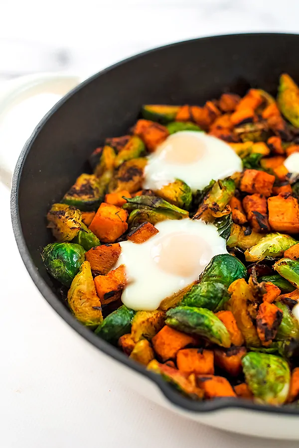 Sweet potato hash with eggs in a cast iron skillet.