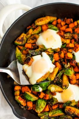 Spatula holding a serving of sweet potato hash and an egg.