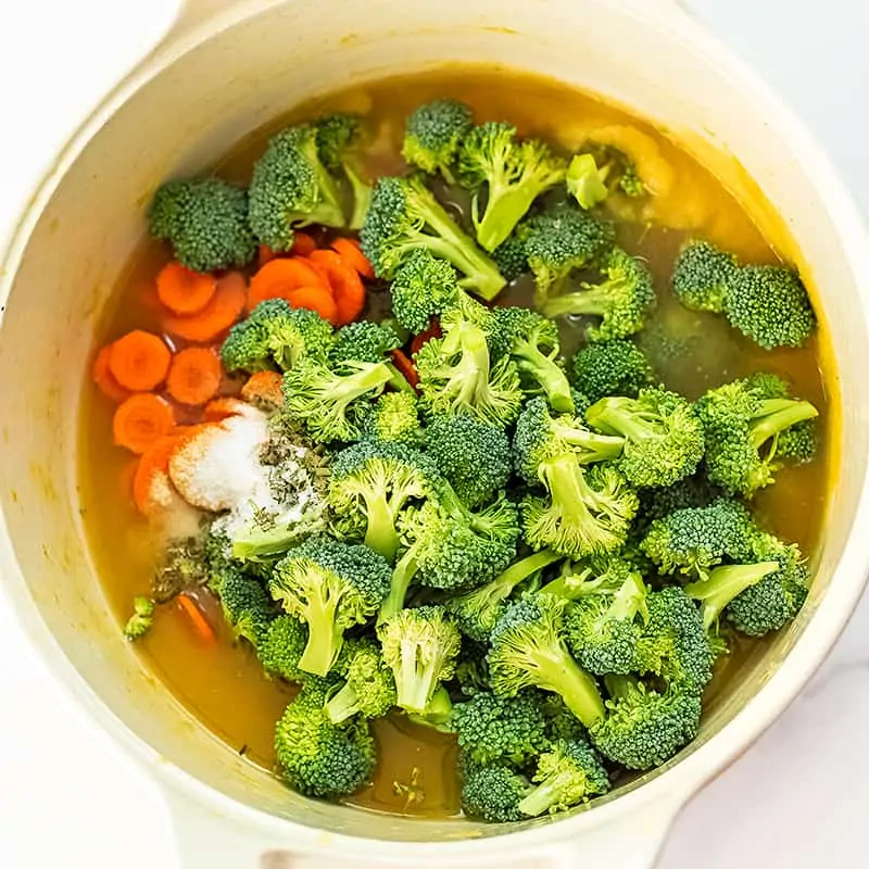 Pot full of broccoli, carrots, broth, salt and seasoning.