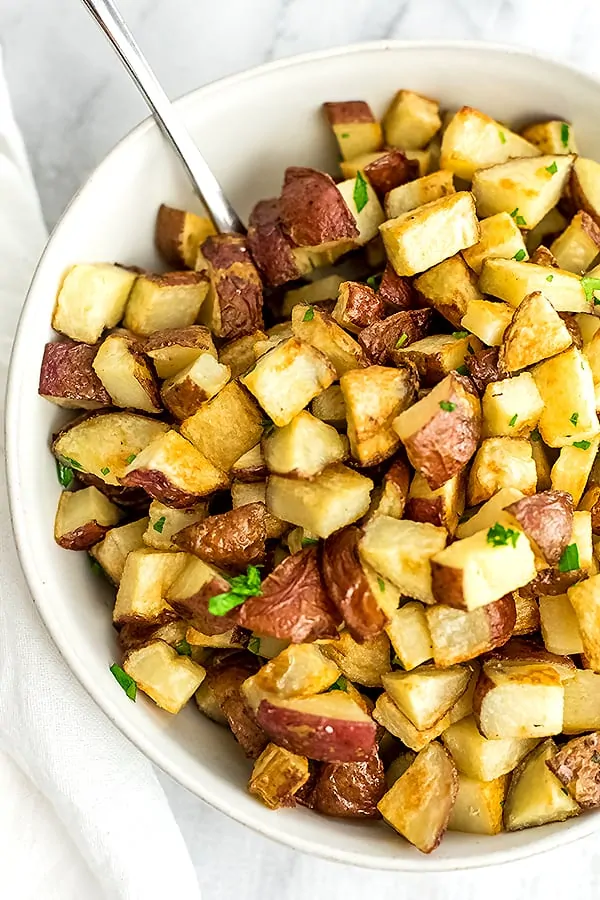 White bowl filled with roasted potatoes.