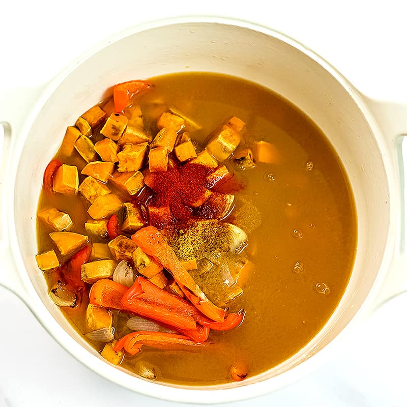 Roasted vegetables, vegetable broth and spices in a large pot before blending.