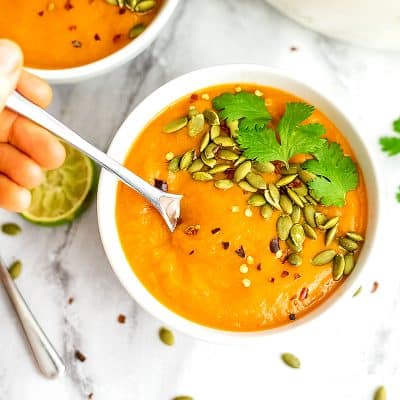 Spoon in a bowl of sweet potato red pepper soup.