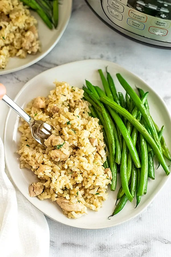 Instant Pot Brown rice and chicken thighs on a plate with green beans.