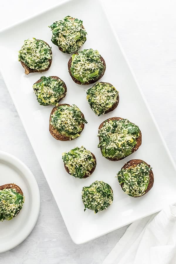 Rectangular plate filled with spinach artichoke stuffed mushrooms.
